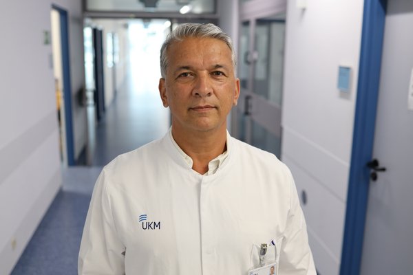 UKM | Leiter der Sektion Angiologie. Er trägt einen weißen Kittel und lächelt.