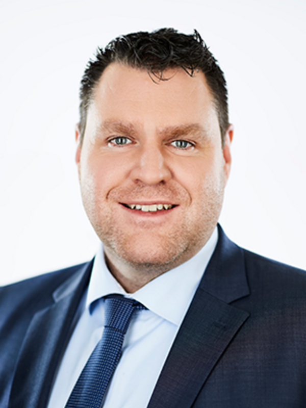 UKM | Klinikdirektor der Neurologie. Er trägt Sakko und Krawatte in Dunkelblau und lächelt.