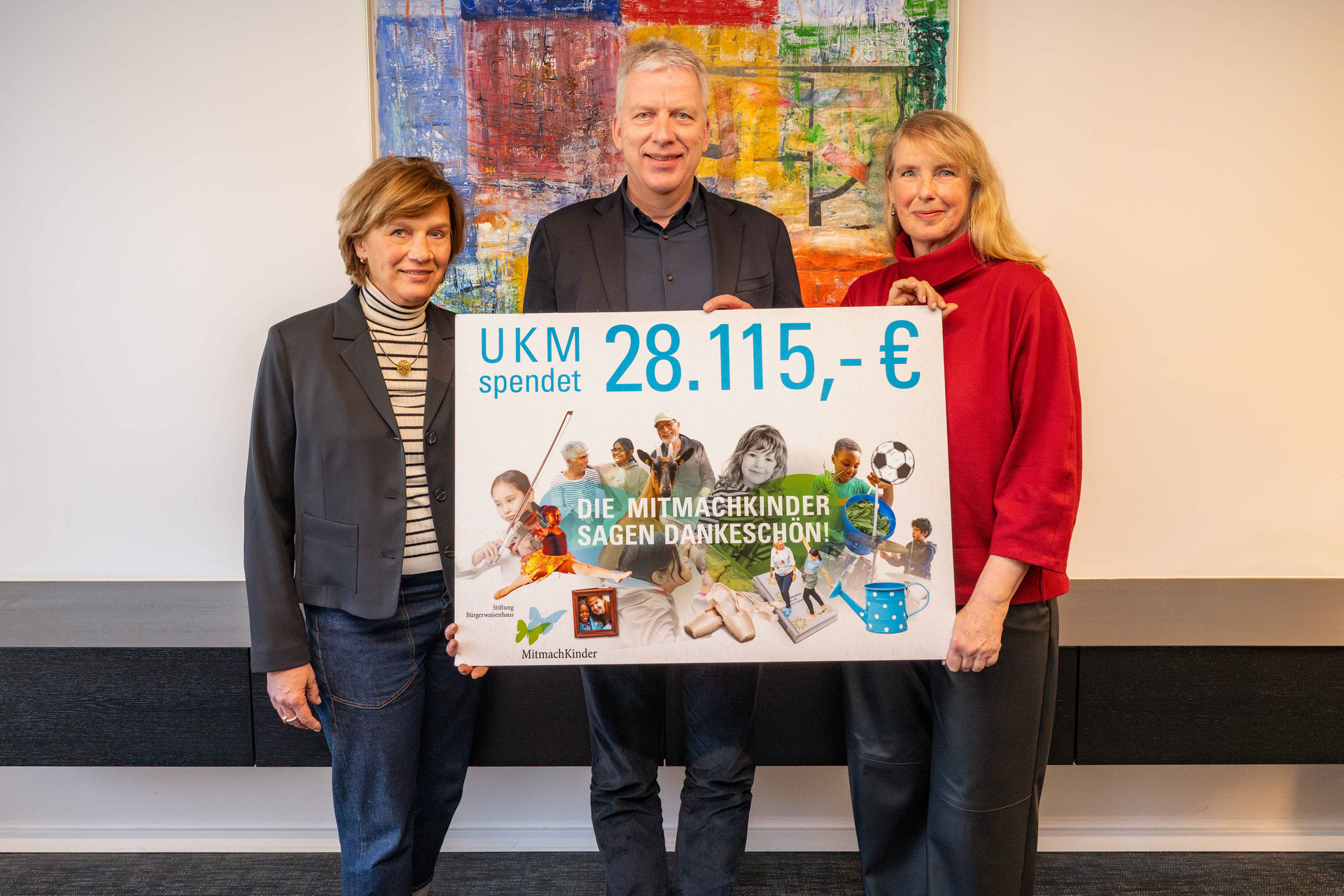 UKM | Spendenübergabe Restcentspende | Martina Kreimann und Christine Westphal von den Kommunalen Stiftungen Münster und UKM-Vorstand Dr. Christoph Hoppenheit halten ein Schild mit dem Betrag: 28115 Euro