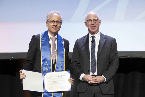 UKM | Zwei Männer lächeln in die Kamera, einer von ihnen hält ein Zertifikat in der Hand.