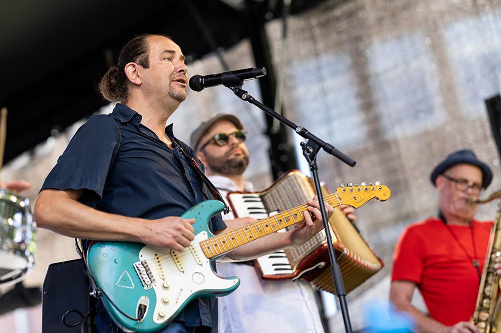 Bühnenmusiker mit E-Gitarre singt am Mikrofon