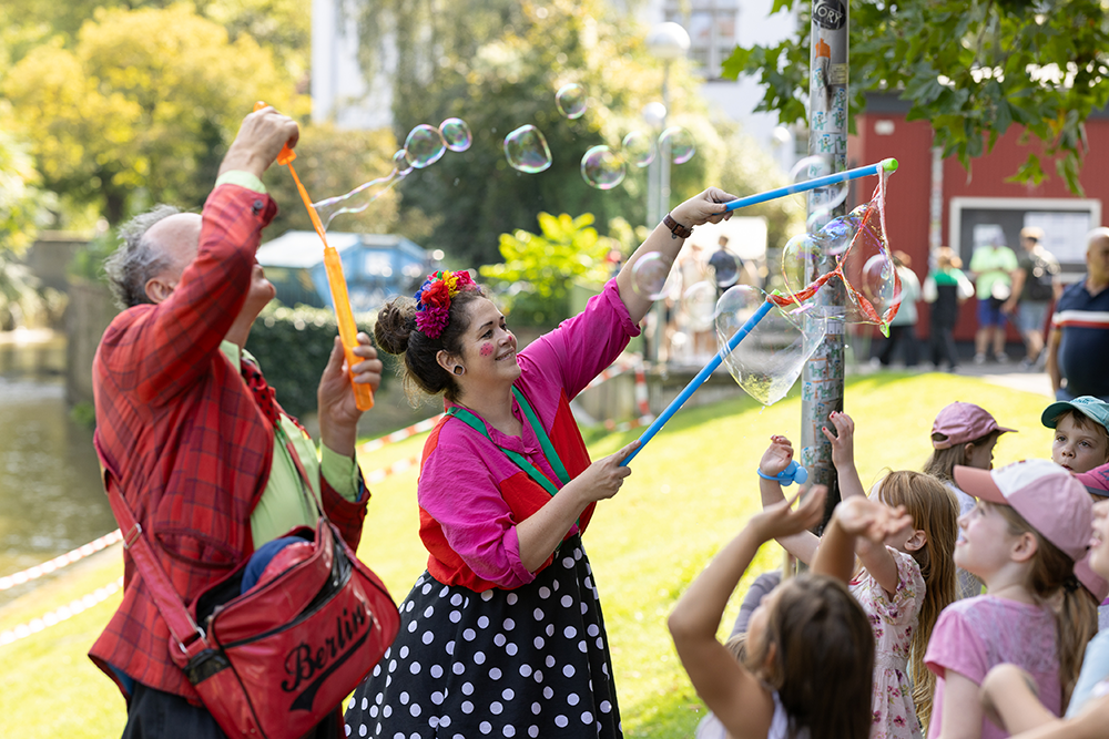 Clownin bläst Riesenseifenblasen auf begeisterte Kinder